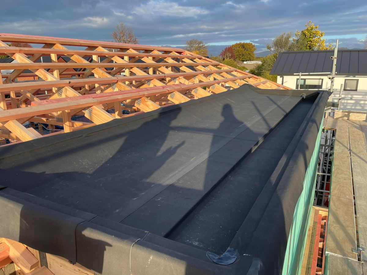 Houten dakstructuur naast een plat dak in aanbouw
