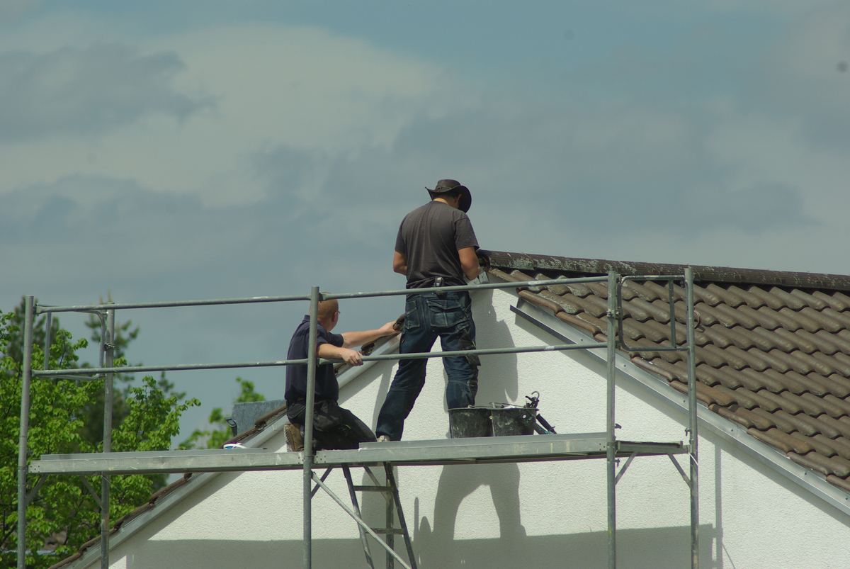 Twee dakwerkers op een stelling aan de puntgevel